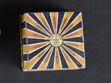 two small boxes with decorative designs on them sitting on a black surface