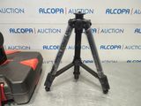 a tripod with a camera on a tripod next to a suitcase