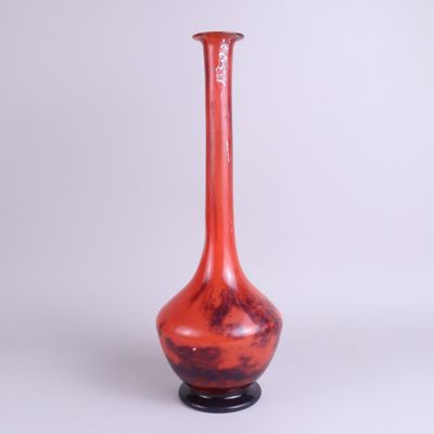 un vase rouge avec un socle noir sur fond blanc