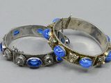 pair of silver bangles with blue glass beads on a gray surface