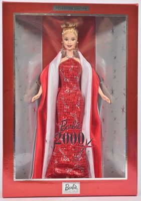 La poupée Barbie se trouve dans une boîte rouge avec une cape blanche.