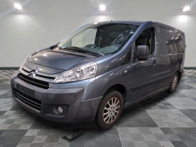 La camionnette grise est garée sur un sol en carrelage à damier.