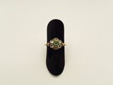 an emerald and diamond ring on a black velvet ring holder