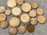 a pile of coins sitting on top of a carpet next to a cup