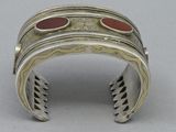 silver cuff bracelet with red and black stones on it