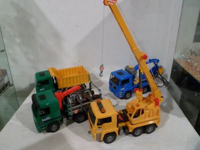 two toy trucks and a crane on display in a glass case
