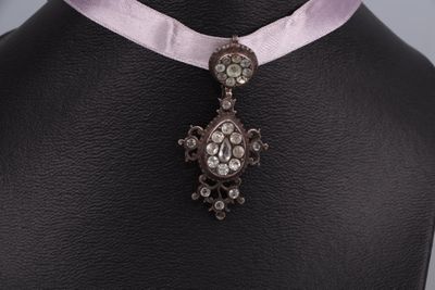 collier orné d'un ruban rose et d'un pendentif en forme de croix, porté par un mannequin