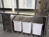 trois poubelles posées devant une fenêtre dans une cuisine