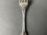 an old silver fork with a flower design on it on a table