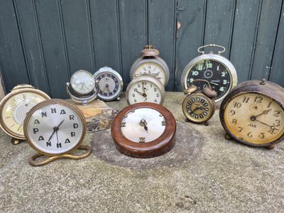 many different types of clocks sitting on the ground