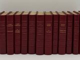 six livres rouges sont alignés sur une surface blanche
