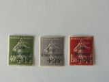 three different postages of different colors on a white surface