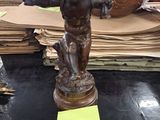 une statue représentant un garçon tenant un panier posé sur une table