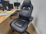 a black office chair sitting in front of a computer desk