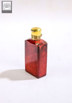 une petite bouteille en verre rouge avec un bouchon doré