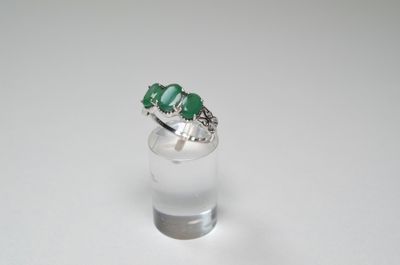 a close up of a ring with three emerald stones on it
