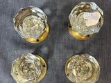 quatre vases en verre aux bords dorés posés sur un tissu gris