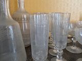bottles and glasses are lined up on a table next to a vase
