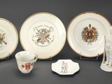 cinq assiettes, un pichet et un vase posés sur une table