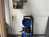 un nettoyeur haute pression bleu posé à côté d'une machine grise et noire