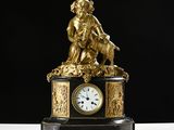 a clock with a statue on top of it on a table