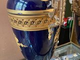 a blue vase on a glass table with a mirror in the background