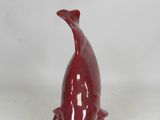 red ceramic whale figurine sitting on a white surface