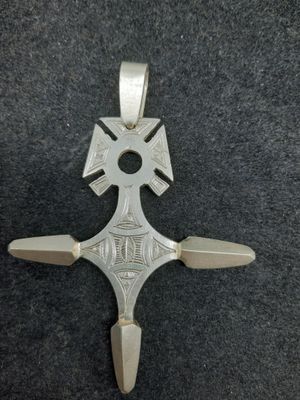 un gros plan d'une croix en argent sur une surface noire