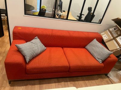 a red couch in a living room with a mirror on the wall