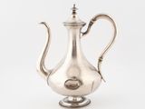 a silver tea pot sitting on a white surface