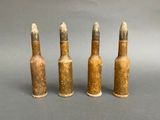 three old metal bullet shells are lined up on a gray surface