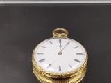 une montre de poche en or posée sur une surface noire