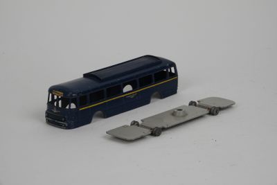 un petit bus en plastique posé à côté d'un morceau de métal