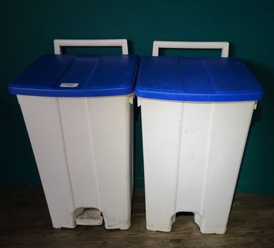 two white and blue trash cans sitting next to each other on a wooden floor