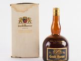 une vieille bouteille de Grand Marnier posée à côté d'une boîte en carton