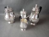 three pieces of silver tea and coffee set sitting on a table
