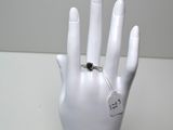 une main de mannequin blanche tenant une bague à laquelle est attachée une étiquette