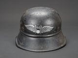 an old helmet with a winged emblem on it on a gray background