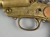 a brass gun with a wooden handle on a white surface