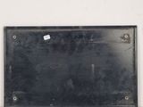 a black plaque on a white wall with a sticker on it