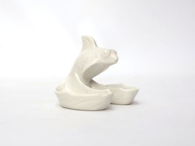 a white ceramic sculpture of a cat on a white surface
