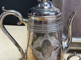 a silver tea pot sitting on a table next to a mirror