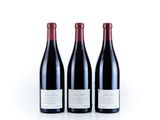 three bottles of red wine are lined up on a white surface