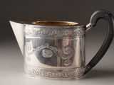 a silver pitcher sitting on a table with a black handle