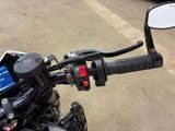 a close up of a motorcycle handlebar with a car in the background