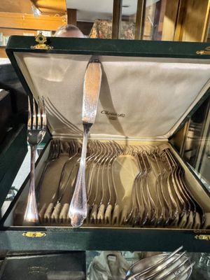 des couverts présentés dans un étui vert, exposés dans un magasin