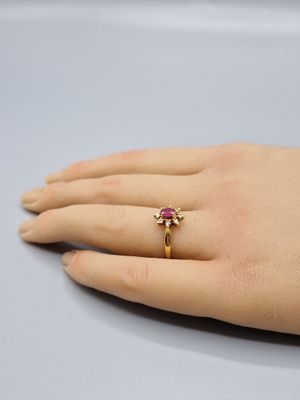 la main de quelqu'un, ornée d'une bague en or sertie d'une pierre rose