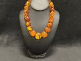 a necklace made of orange and yellow glass beads on a mannequin