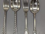 quatre cuillères en argent et une fourchette sont alignées sur une table