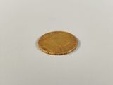 a small gold coin sitting on top of a white surface